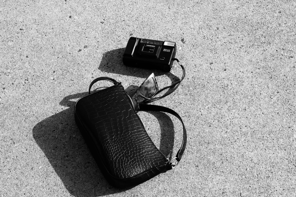 uma foto em preto e branco de uma câmera e uma bolsa