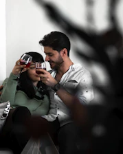 Happy couple exchanging a custom wine bottle gift during a cozy dinner celebration.