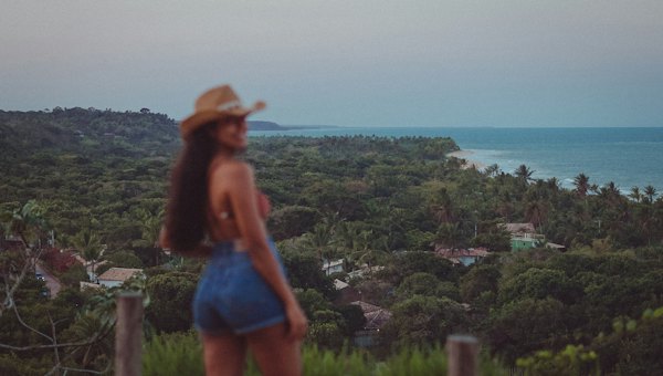 A walker at a lookout over the forest and the sea — Trancoso, Brazil