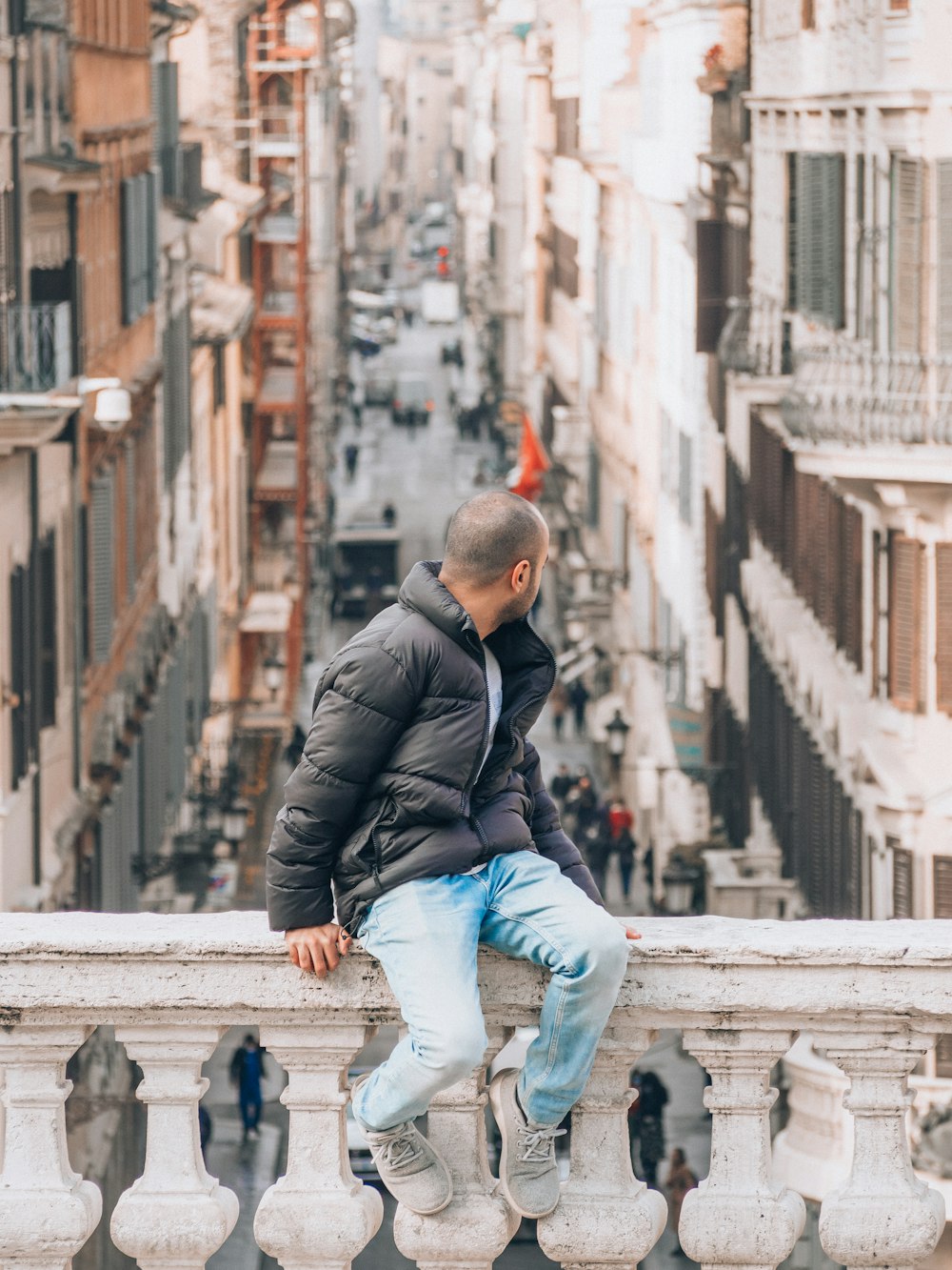 a man sitting on top of a balcony next to a building