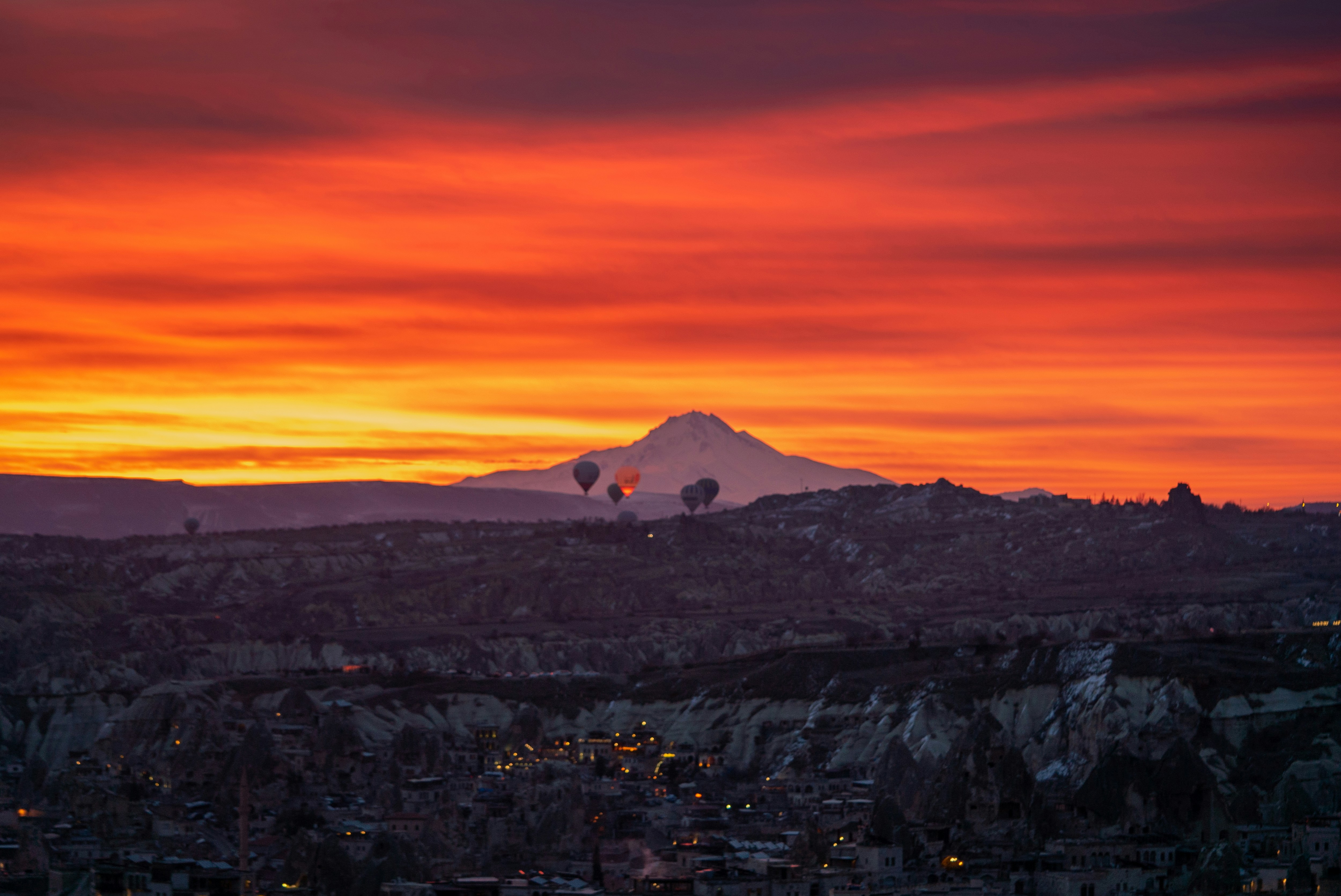a sunset view of a mountain with hot air balloons in the sky