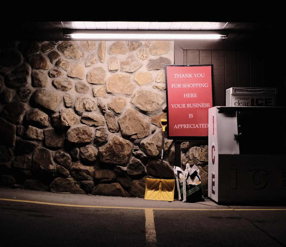 un muro di pietra con un cartello su di esso che dice grazie per lo shopping qui il tuo