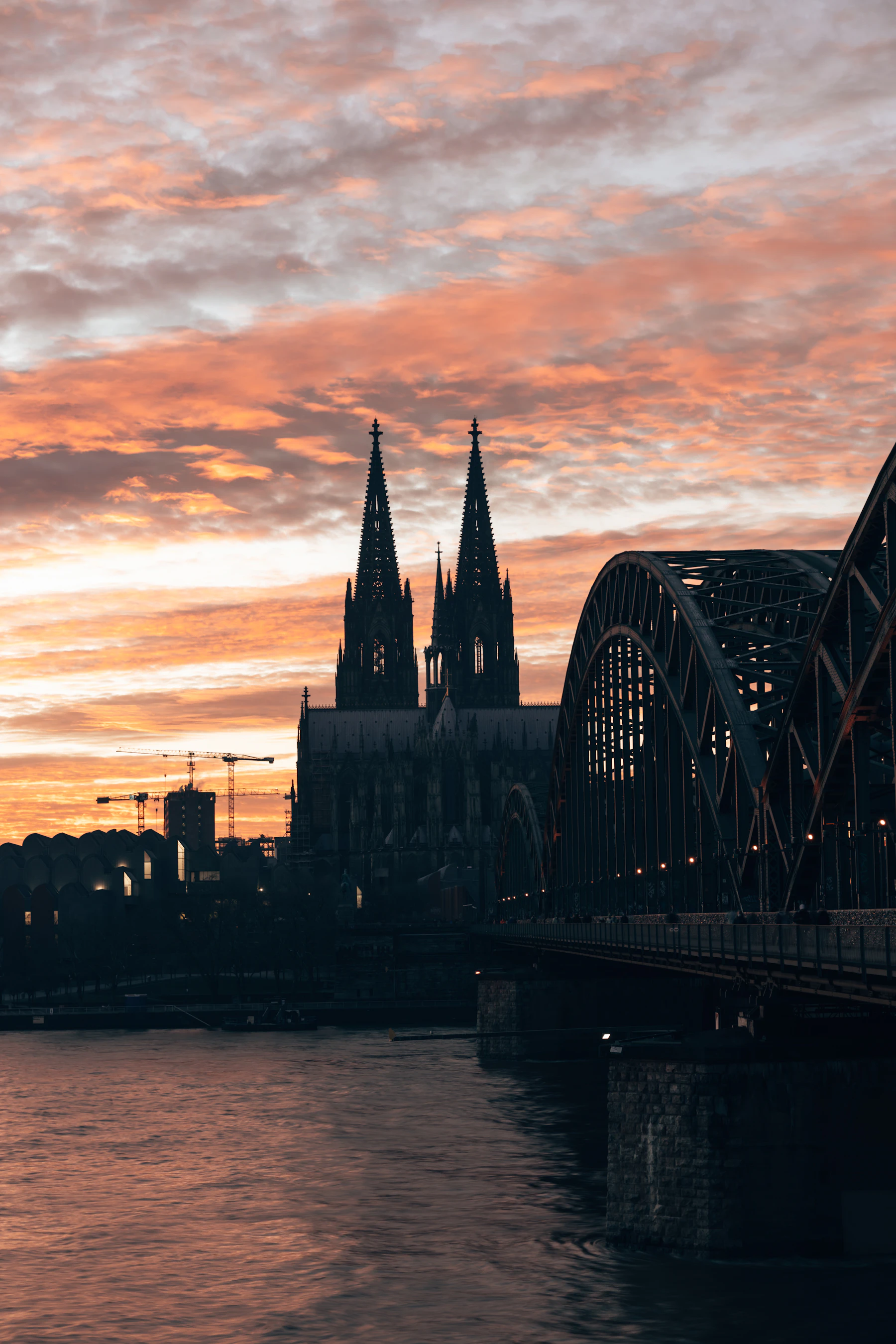 Kölner Dom und Brücke bei Sonnenuntergang über dem Rhein