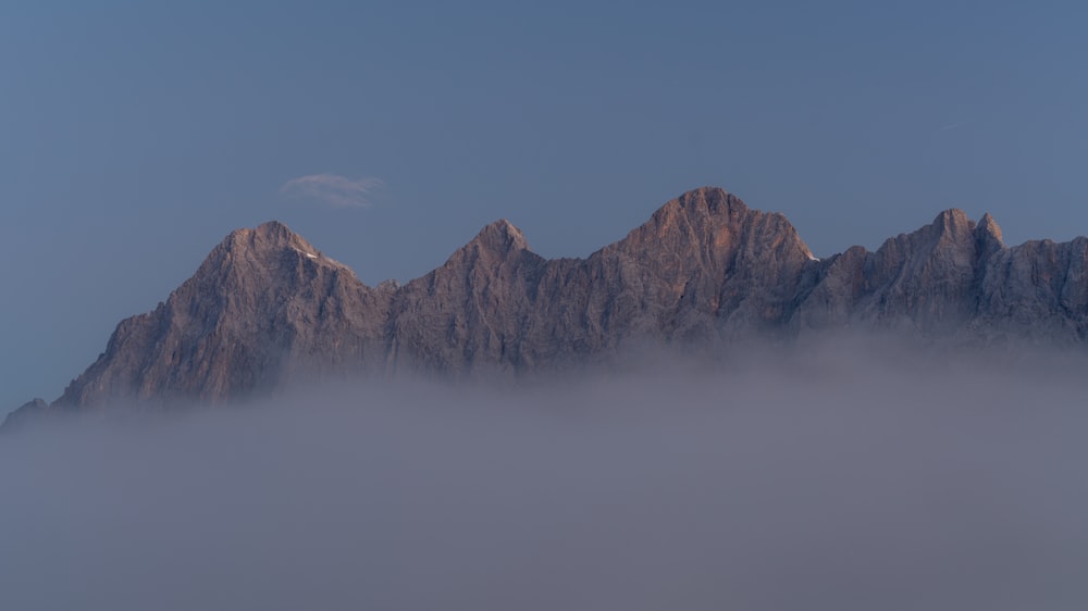 Una montagna molto alta coperta di nebbia sotto un cielo blu