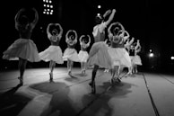 A group of dancers rehearsing a theatrical ballet performance on stage.