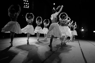 A group of ballet dancers practicing on stage with theatrical lighting.