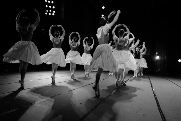A group of ballet dancers practicing on stage with theatrical lighting.
