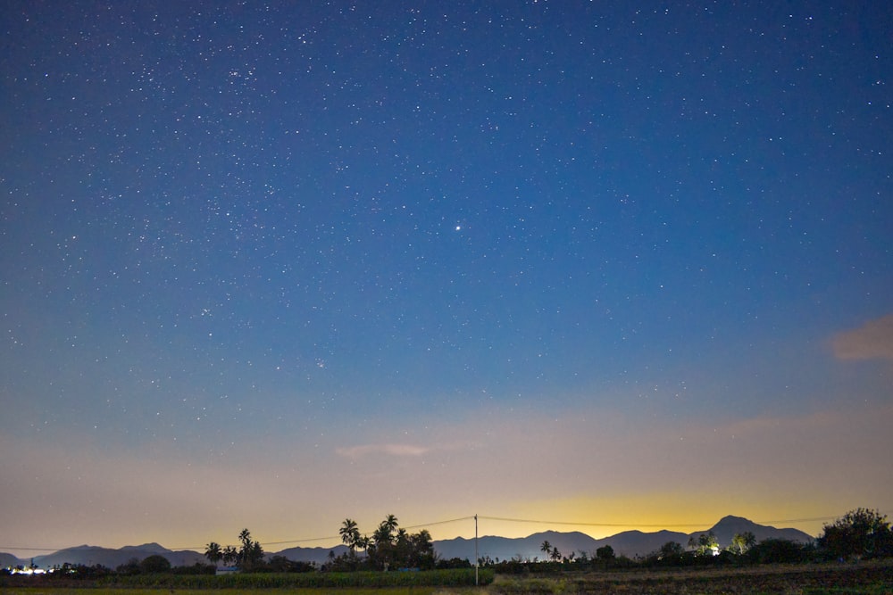 the night sky with stars above the mountains