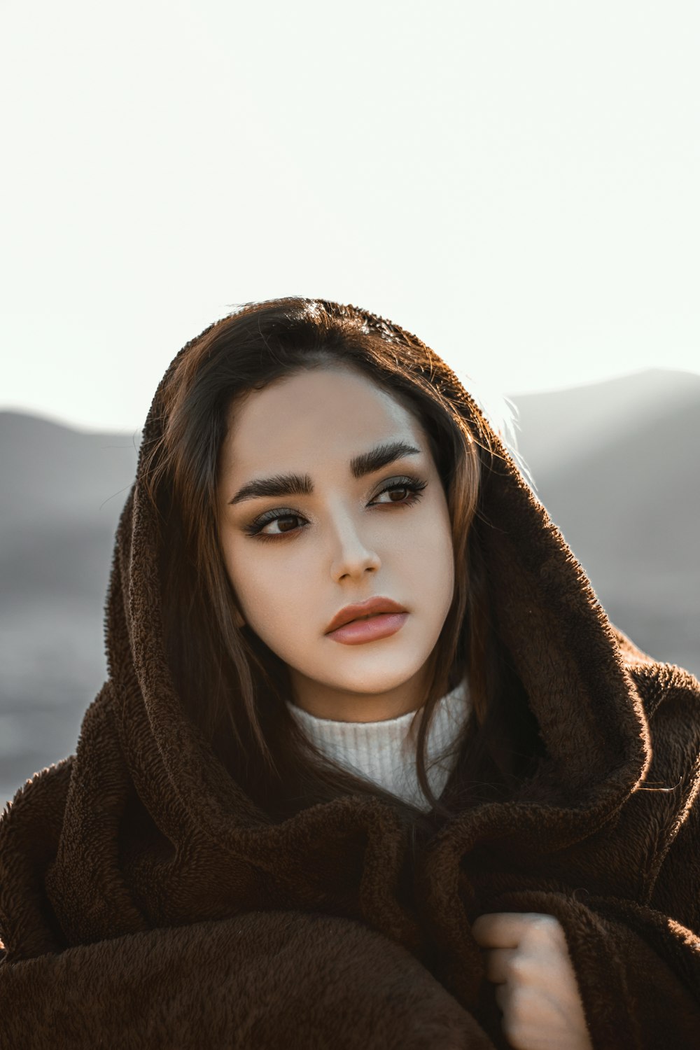 a woman wearing a brown hooded jacket