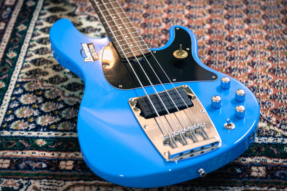 a blue electric guitar sitting on top of a rug