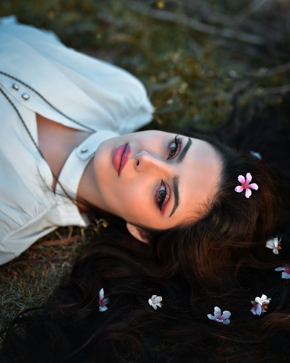 a woman laying on the ground with flowers in her hair