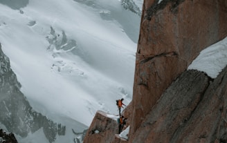 a man standing on the side of a snow covered mountain