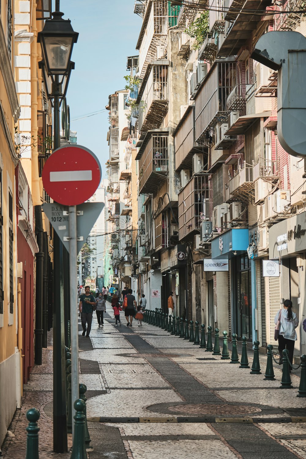 a group of people walking down a street next to tall buildings