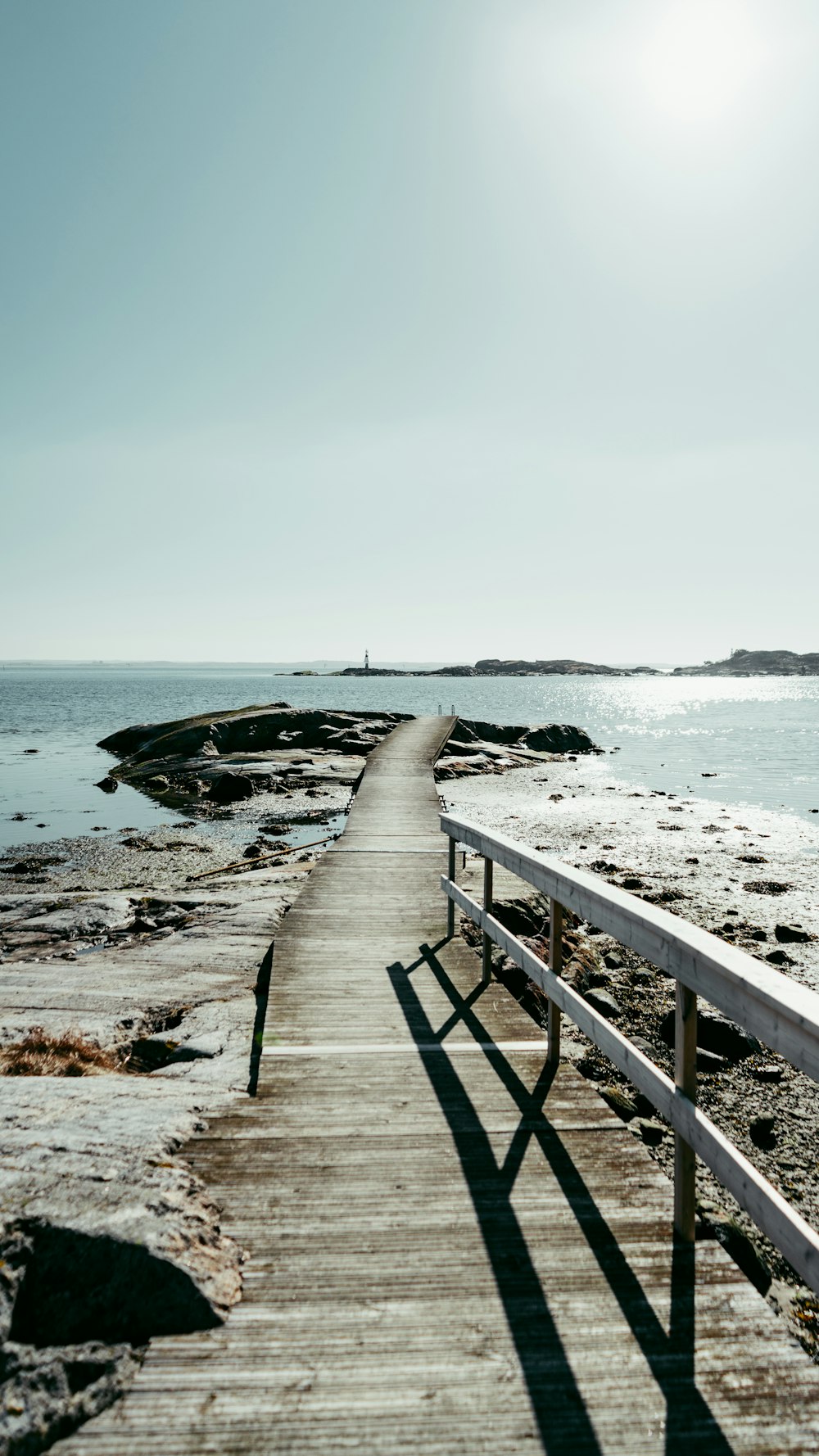 a wooden walkway leading to the ocean on a sunny day