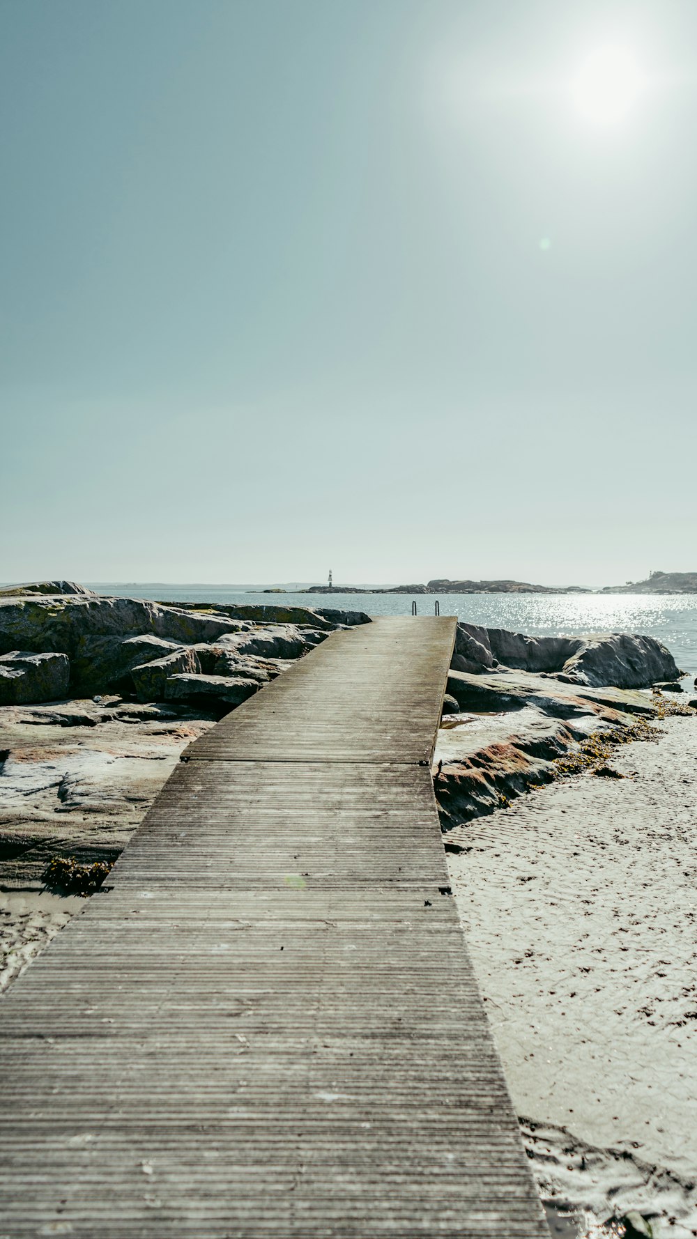 a wooden walkway leading to the ocean on a sunny day