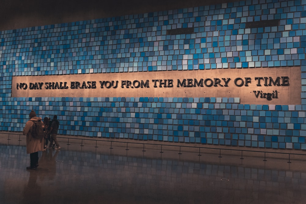 a person standing in front of a blue tiled wall