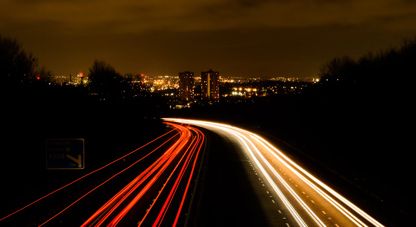 Rodovia à noite com rastros de luz dos veículos em movimento