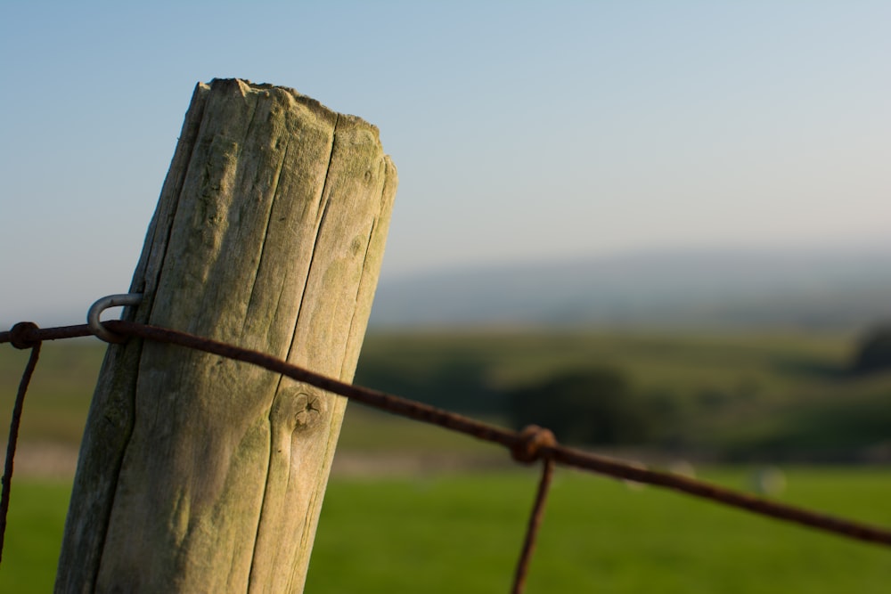 a wooden post with a barbed wire fence