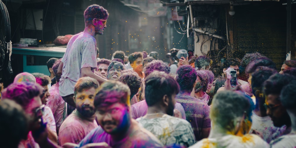 a man standing in front of a crowd of people covered in colored powder