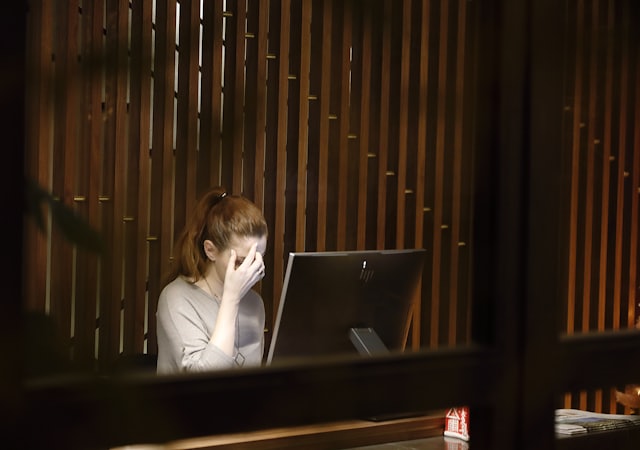 Frau am Laptop fasst sich an die Schläfen