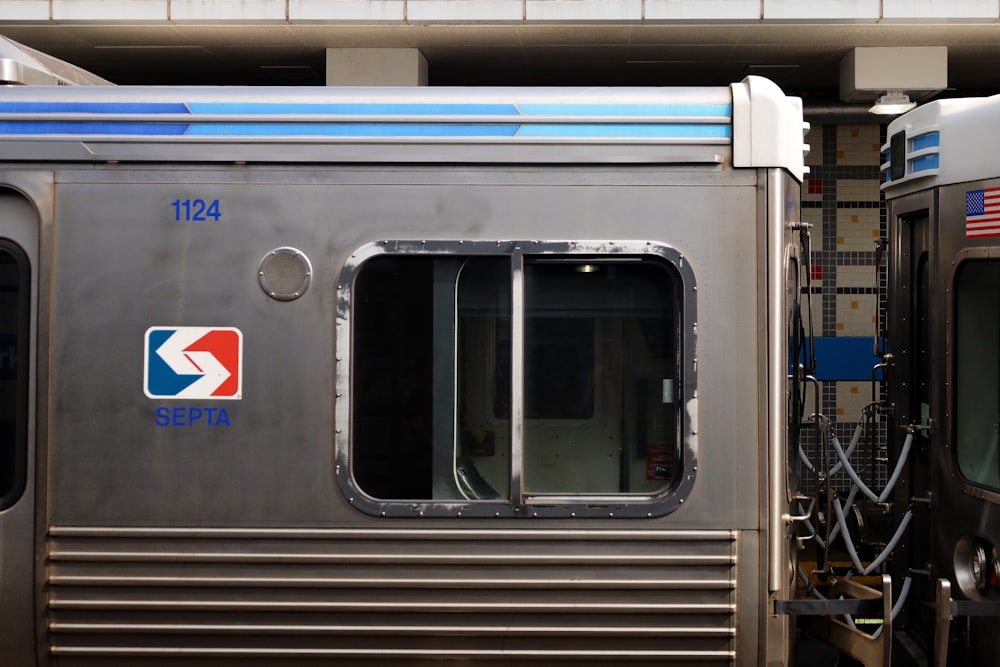 a silver train parked next to a loading platform