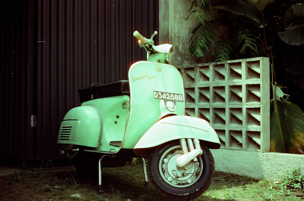 a green scooter parked next to a building
