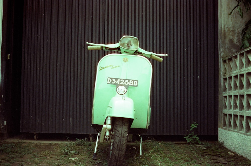 a green scooter parked in front of a building