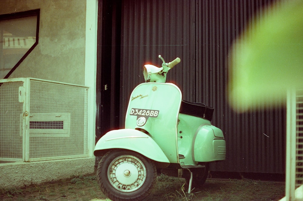 a green scooter parked in front of a building