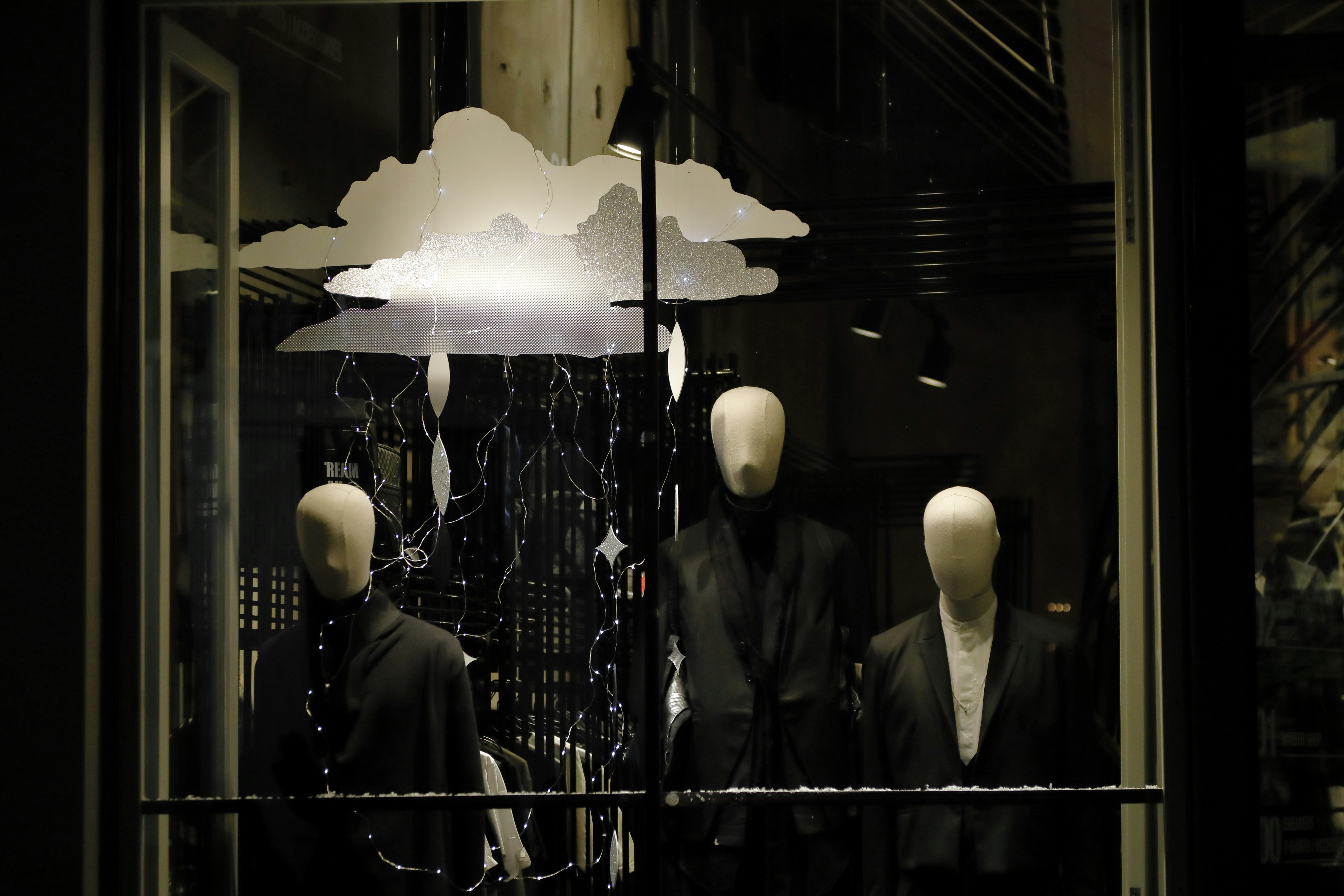 three mannequins dressed in suits and jackets in a window