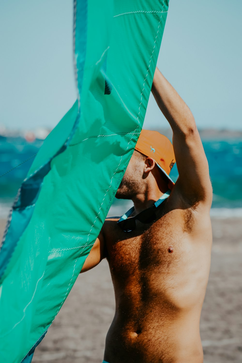 a shirtless man holding a kite on the beach