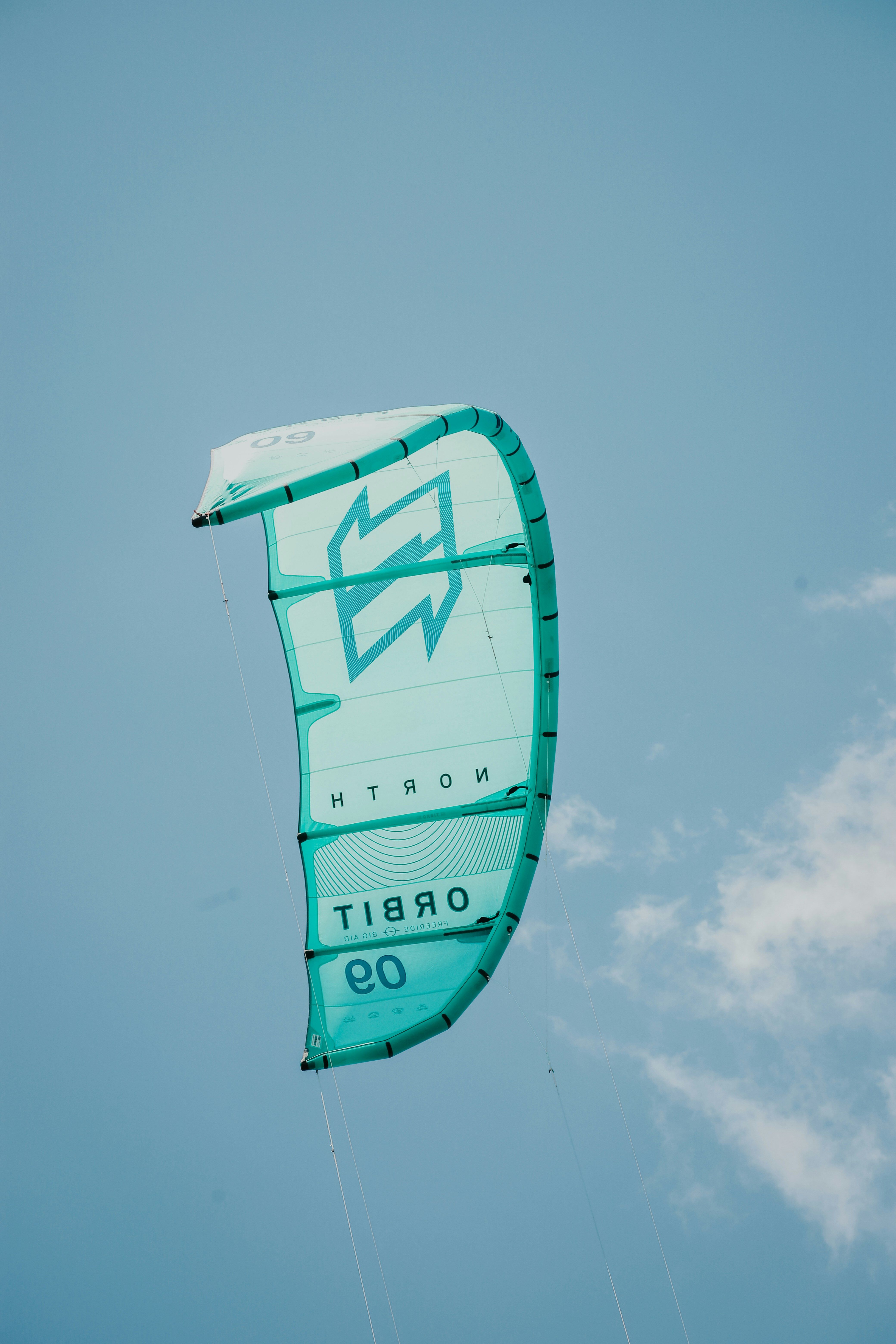 a large green kite flying through a blue sky