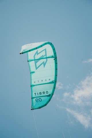 a large green kite flying through a blue sky