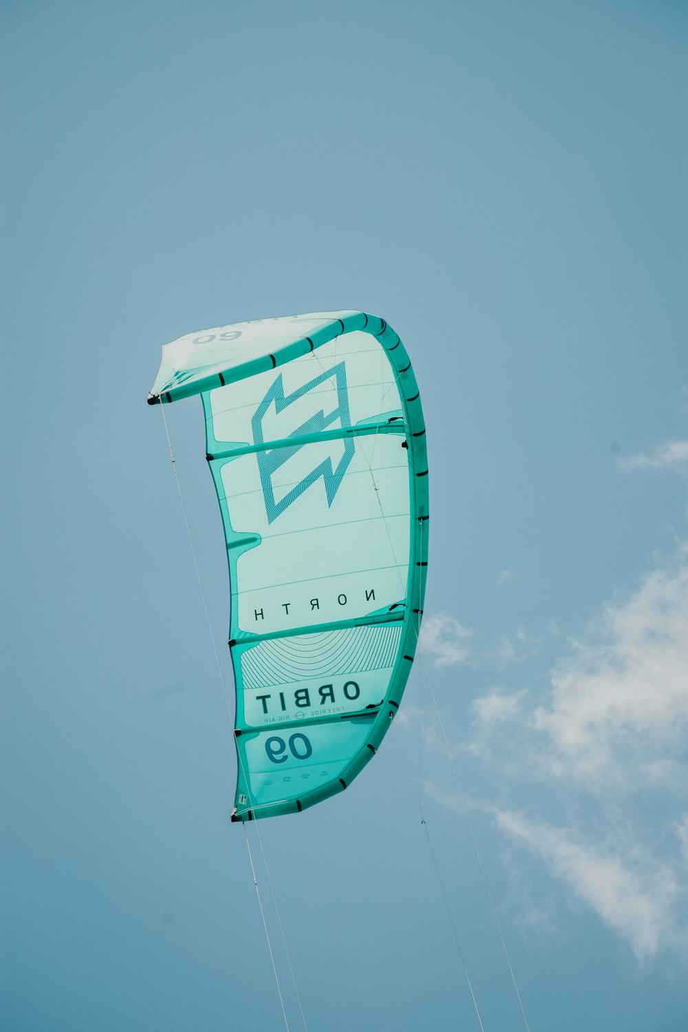 a large green kite flying through a blue sky