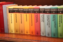 a row of books sitting on top of a wooden shelf