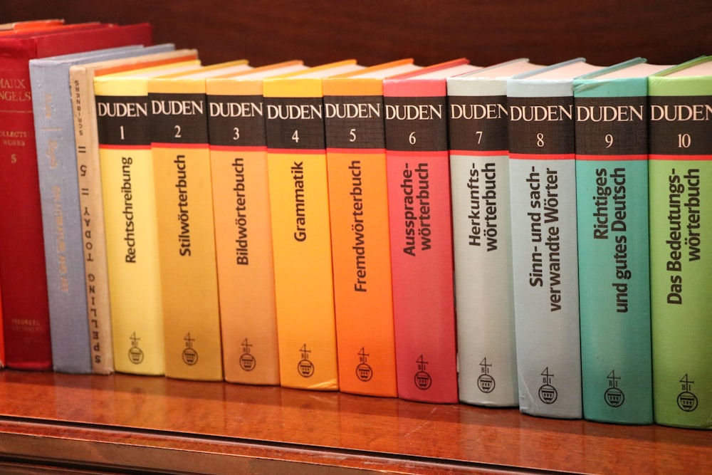 a row of books sitting on top of a wooden shelf