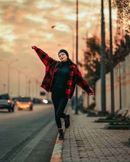 a woman walking down a sidewalk next to a street