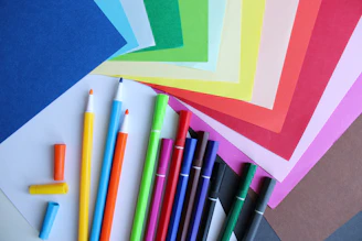 a bunch of different colored paper and pens