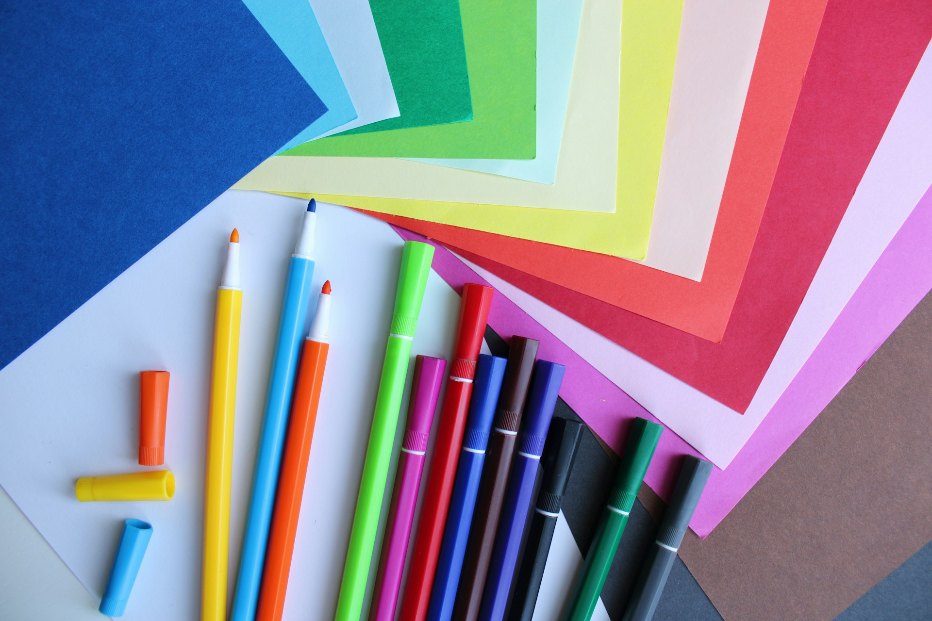 a bunch of different colored paper and pens