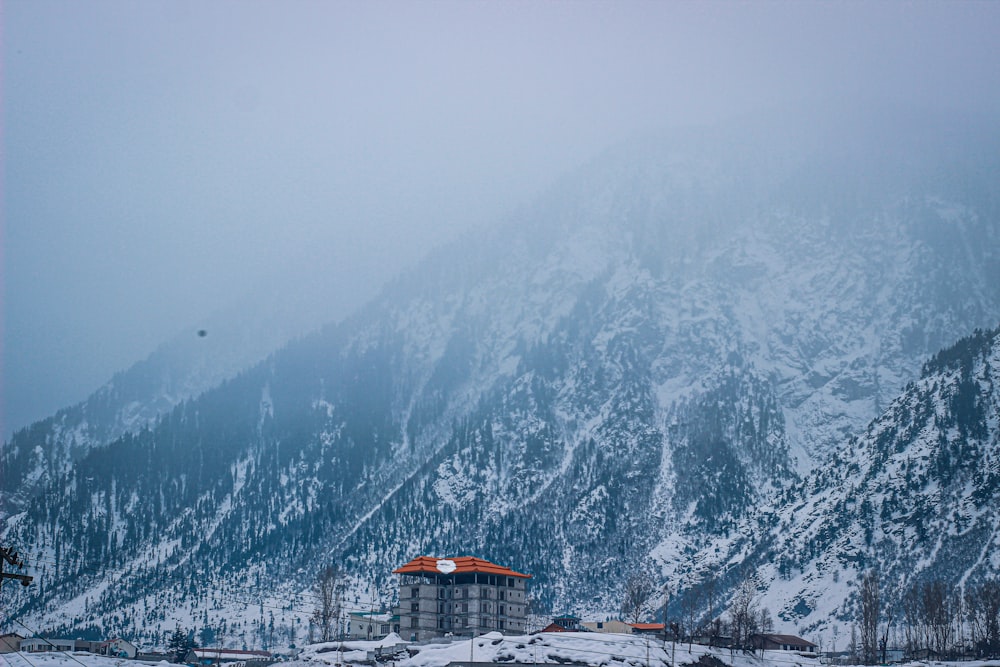 a snow covered mountain with a house in the foreground