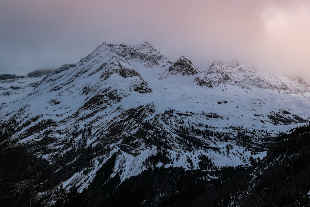 a mountain covered in snow under a cloudy sky