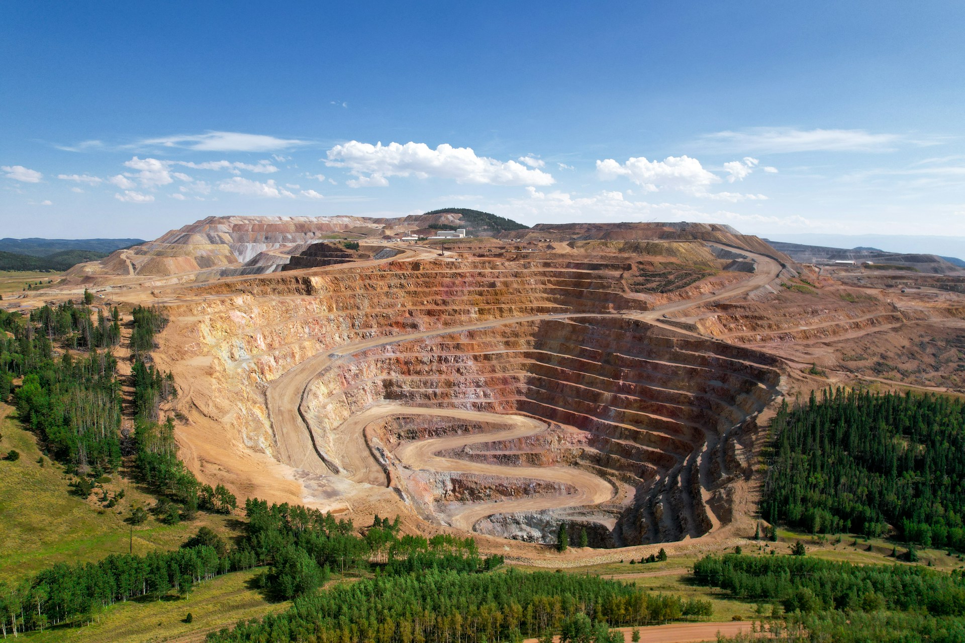 a large open pit in the middle of a forest