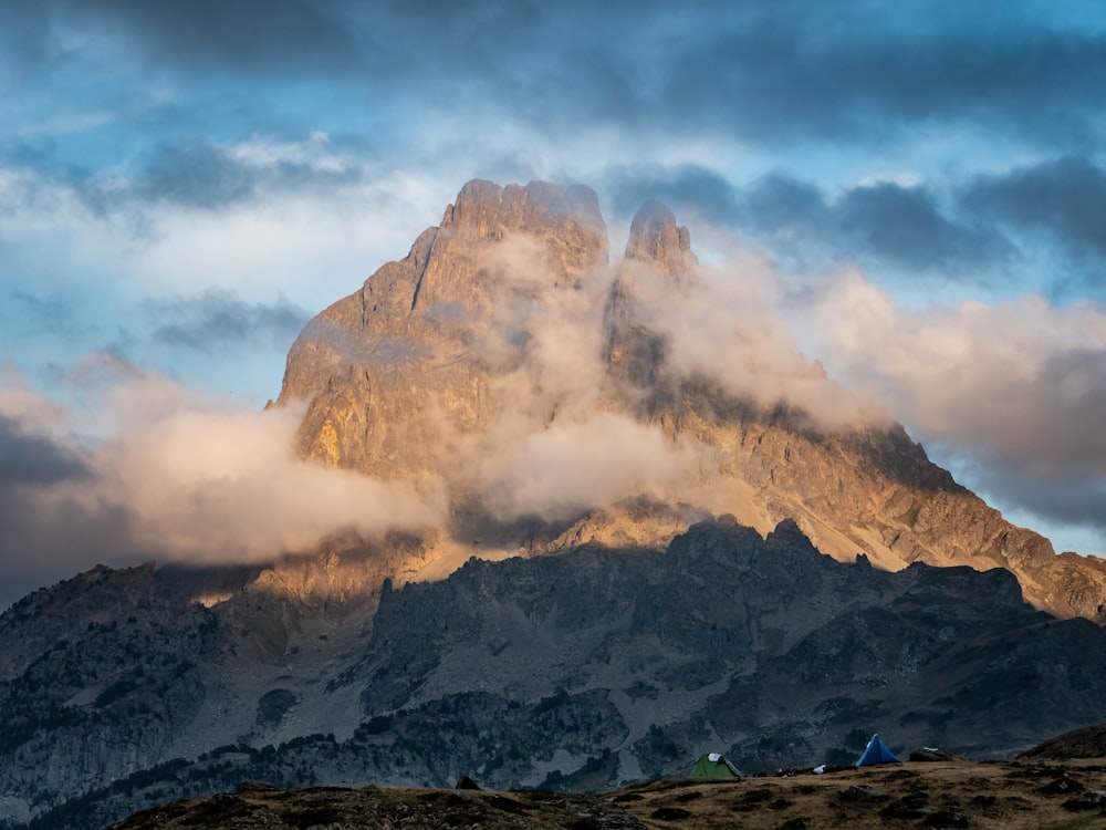 uma montanha muito alta com algumas nuvens no céu