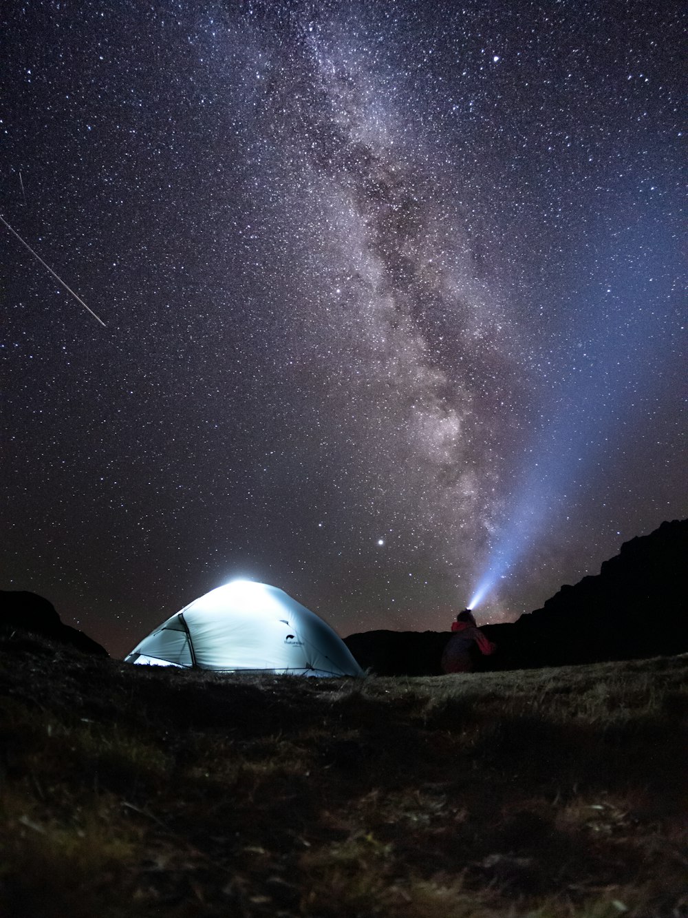 uma tenda no meio de um campo sob um céu noturno cheio de estrelas