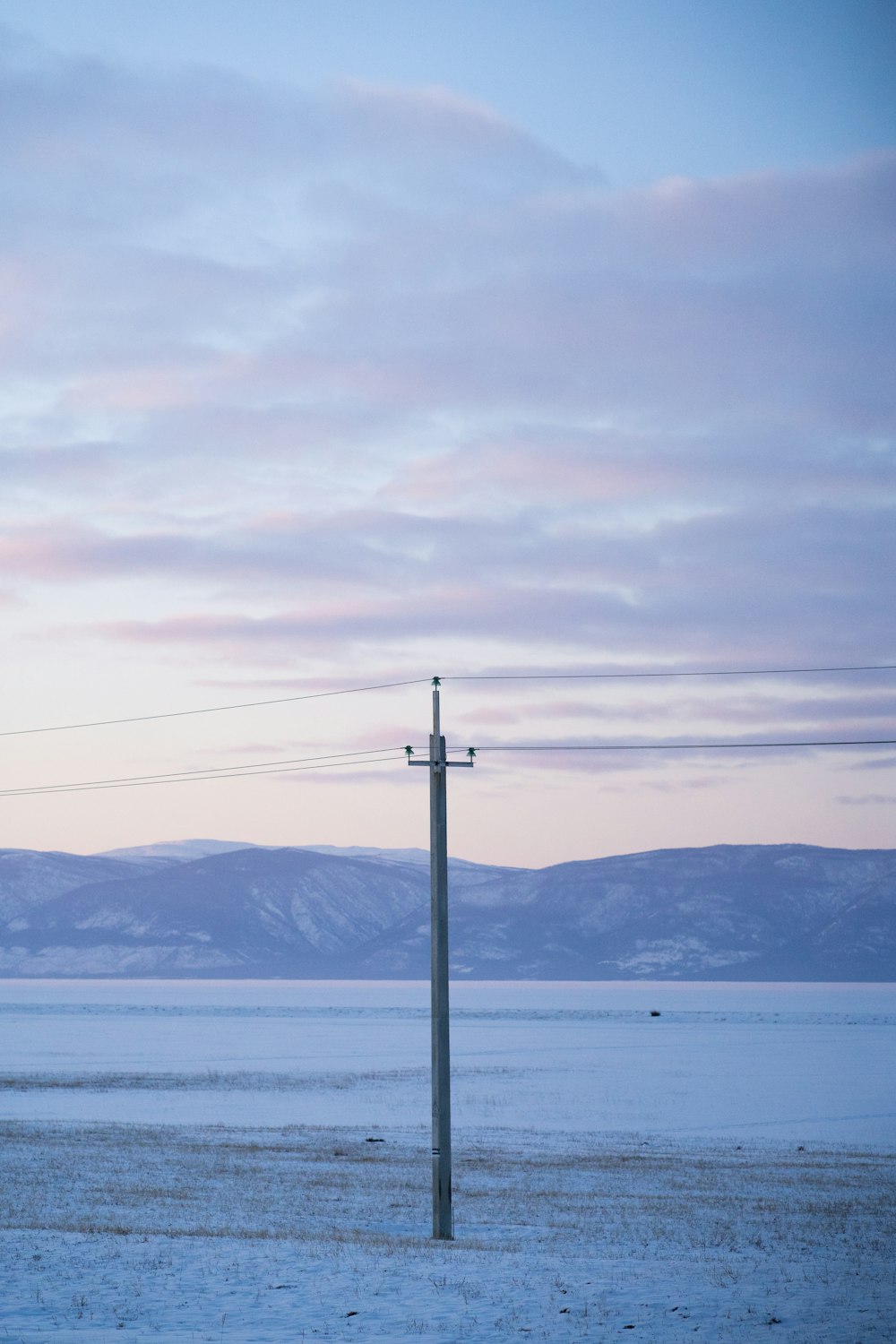 a telephone pole sitting in the middle of a snow covered field