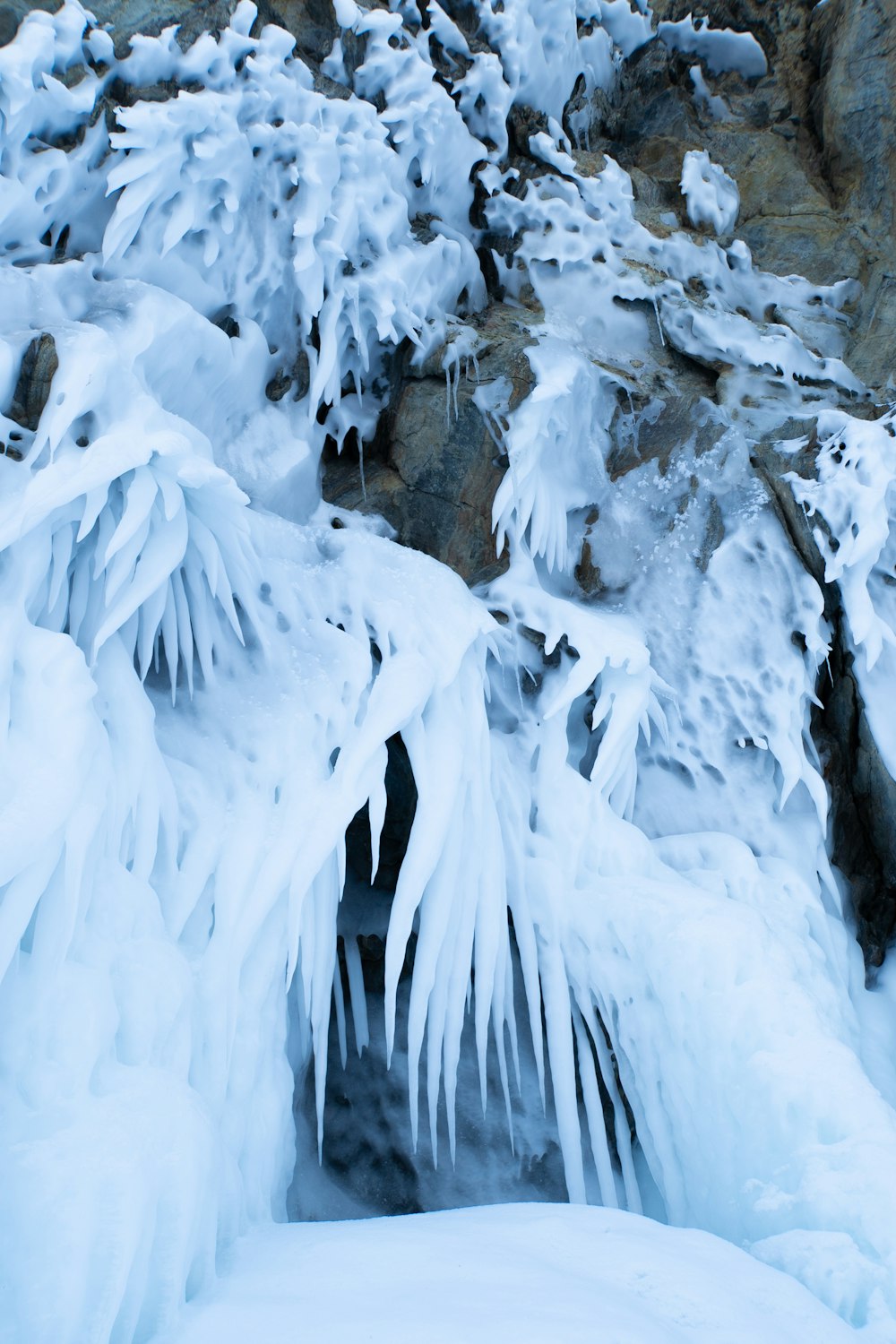 a snow covered mountain with ice hanging off of it's sides