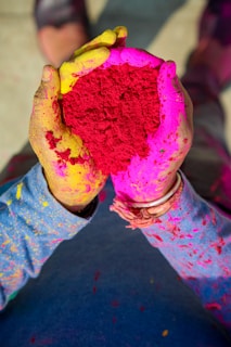 Close-up of hands covered in bright Holi colors holding eco-friendly powder packets