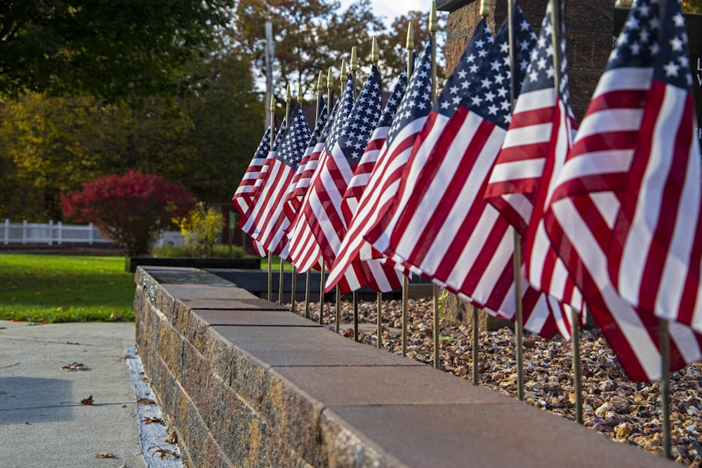 a row of american flags on a stone wall