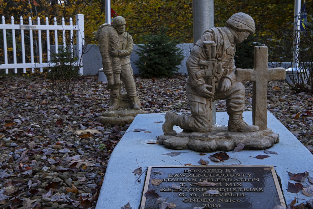 a statue of two soldiers in front of a white picket fence