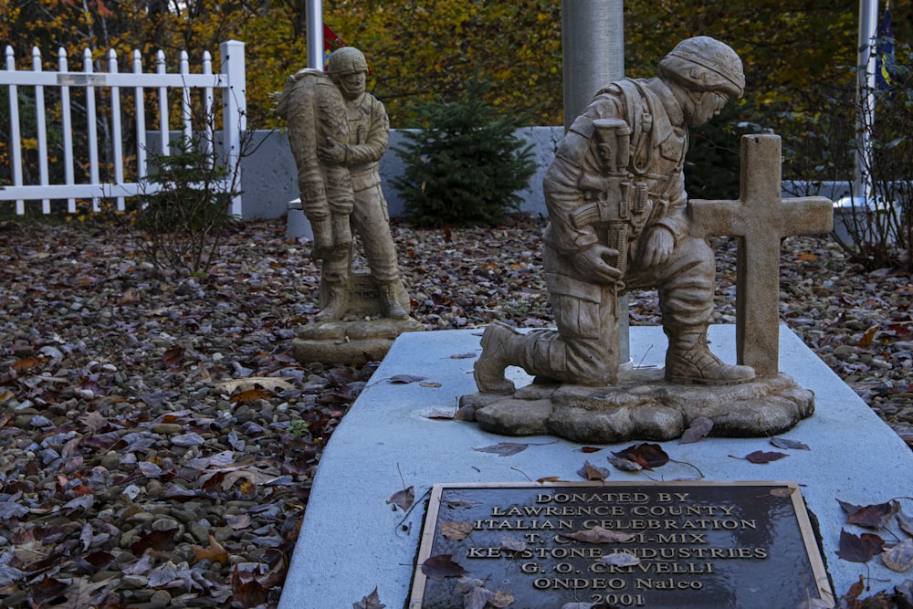 Una estatua de dos soldados frente a una valla blanca