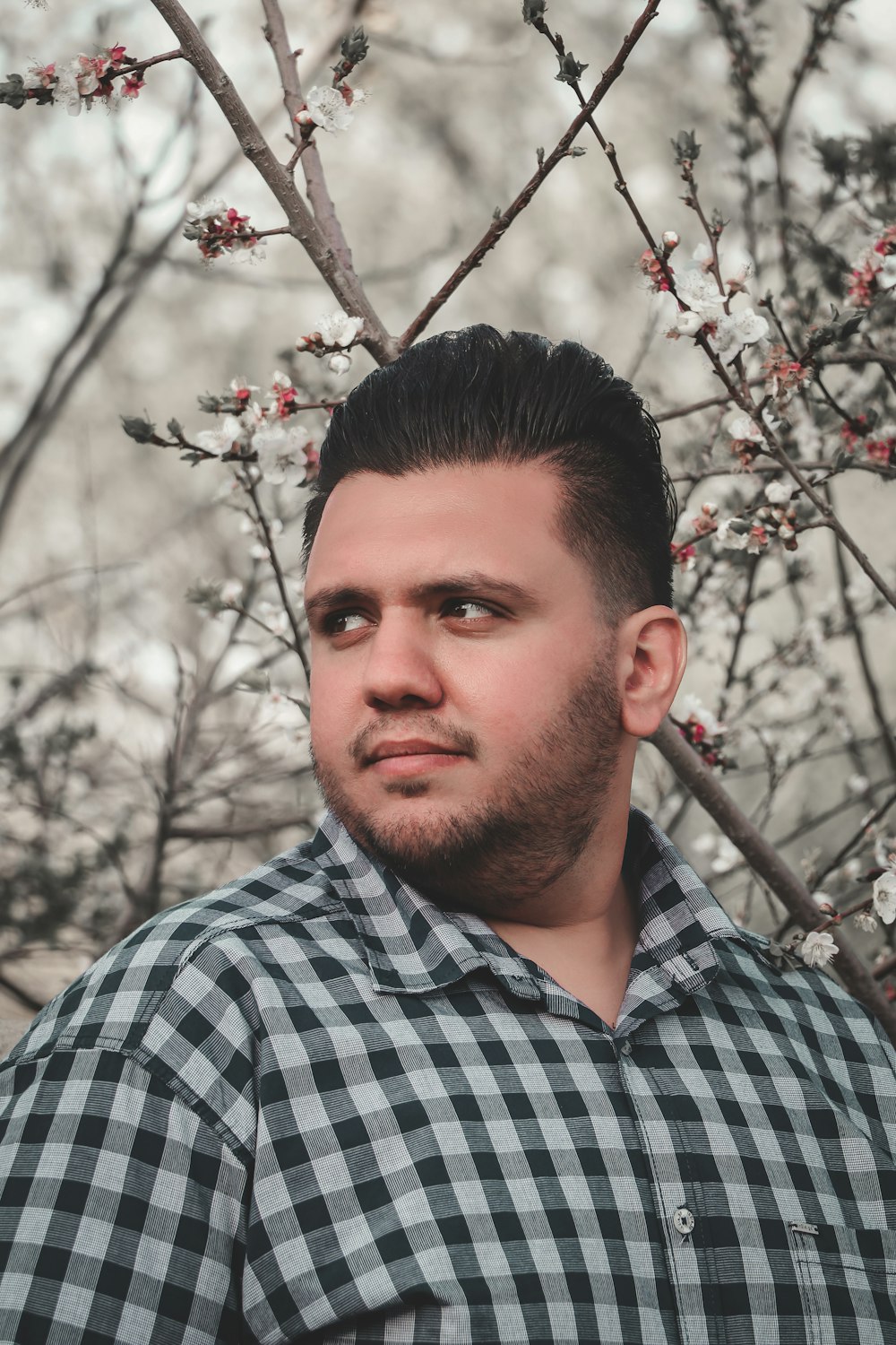 a man standing in front of a tree with flowers